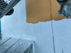 外壁中塗り作業の様子。ローラーでムラなく丁寧に塗布しています。